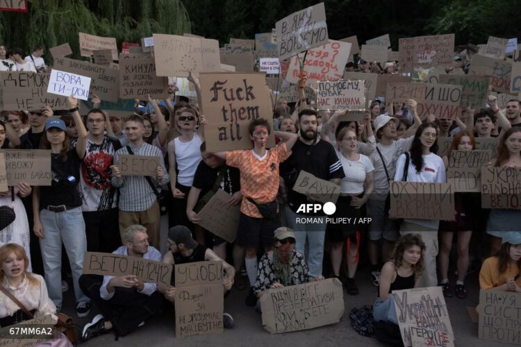 Protesters hold placards during a demonstration against a law that removes the independence of two key anti-corruption bodies in downtown Kyiv on July 23, 2025, amid the Russian invasion of Ukraine. The mostly young marchers urged the Ukrainian president to veto the legislation in the biggest protest in Kyiv since the start of Russia's invasion of Ukraine in 2022. The bill passed on July 22 is the latest in a series of moves criticised by Ukrainian anti-corruption activists. (Photo by Roman PILIPEY / AFP)
