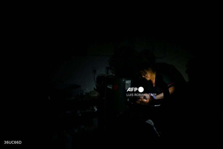 An employee washes a woman's hair during a blackout in Buenos Aires on January 16, 2025. The National Weather Service issued an alert for "extreme temperatures" in central and northern Argentina, affecting 17 of the country's 23 provinces, including Buenos Aires, where due to the heat and high demand for electricity, nearly 40,000 homes suffered blackouts. (Photo by LUIS ROBAYO / AFP)