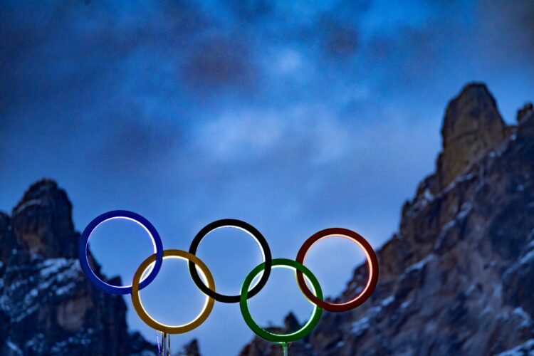 The illuminated Olympic rings are seen on the roof the Olympic stadium with mountain peaks behind it in Cortina d'Ampezzo, northern Italy prior to the Milano Cortina 2026 Olympic Games, on February 2, 2026. (Photo by Odd ANDERSEN / AFP)