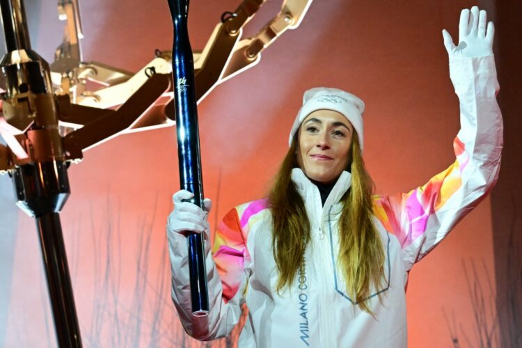 Final torchbearer Italian skier Sofia Goggia holds the torch of the Olympic flame next to the Olympic cauldron designed by Marco Balich during the opening ceremony of the Milano Cortina 2026 Winter Olympic Games at Piazza Angelo Dibona in Cortina d'Ampezzo, northern Italy, on February 6, 2026. (Photo by Stefano RELLANDINI / POOL / AFP)