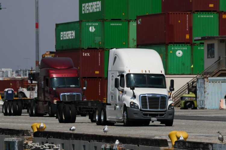(FILES) Trucks drive past cargo shipping containers at the Evergreen shipping terminal at the Port of Los Angeles in Los Angeles, California on September 13, 2025. The US Supreme Court ruled on February 20 that Donald Trump exceeded his authority in imposing a swath of tariffs that upended global trade, blocking a key tool the president has wielded to impose his economic agenda. (Photo by Patrick T. Fallon / AFP)